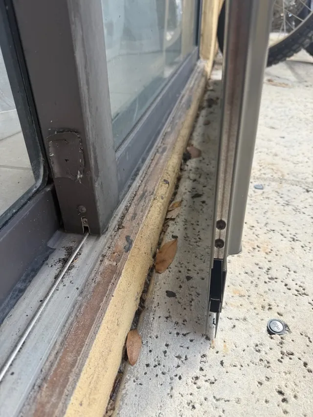 Sliding door panel edge beside an exposed lower track and sill